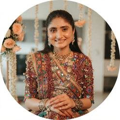 Priya Sharma wearing a printed muslin lehenga set, captured in a warm, festive-themed portrait.
